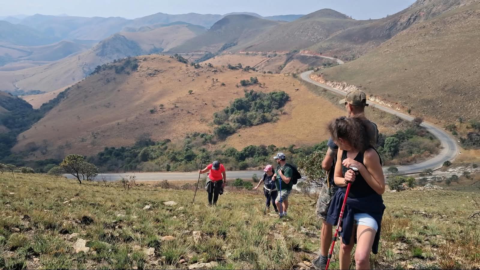 Hikers on a slope above the winding Makhonjwa geotrail pass road