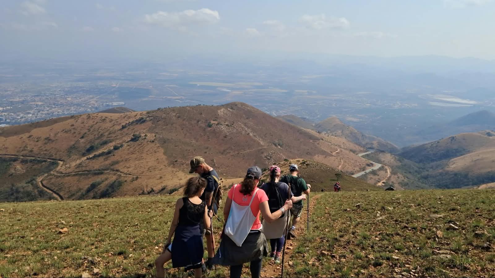 Hikers descending a ridge with a vast lowveld panorama beyond Barberton